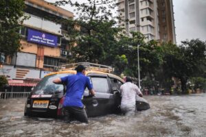 two people pushing a car in a flood