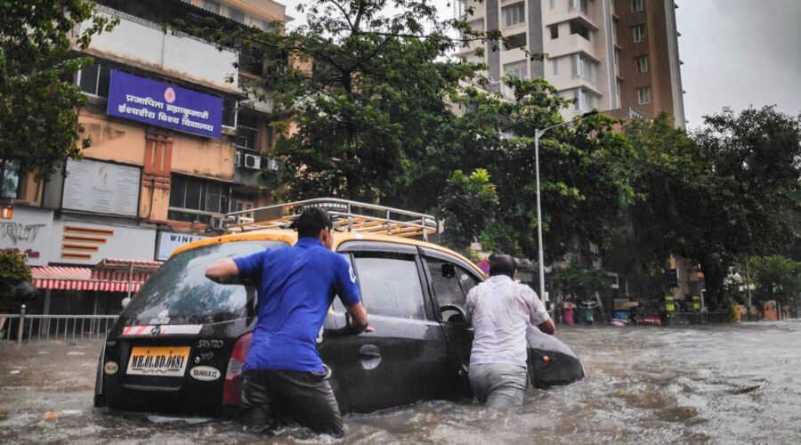 two people pushing a car in a flood
