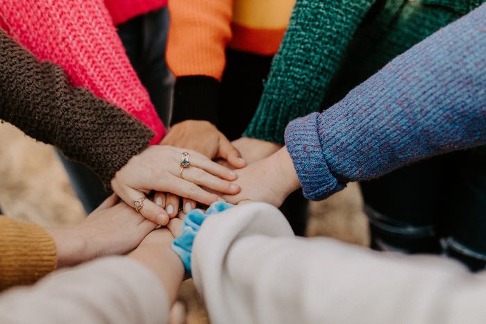 "gathering gifts and gratitude" - a photo of hands placed in the middle, as 8 people reach in together