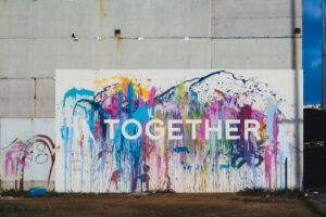 a wall painted in many colors, reads: "together"