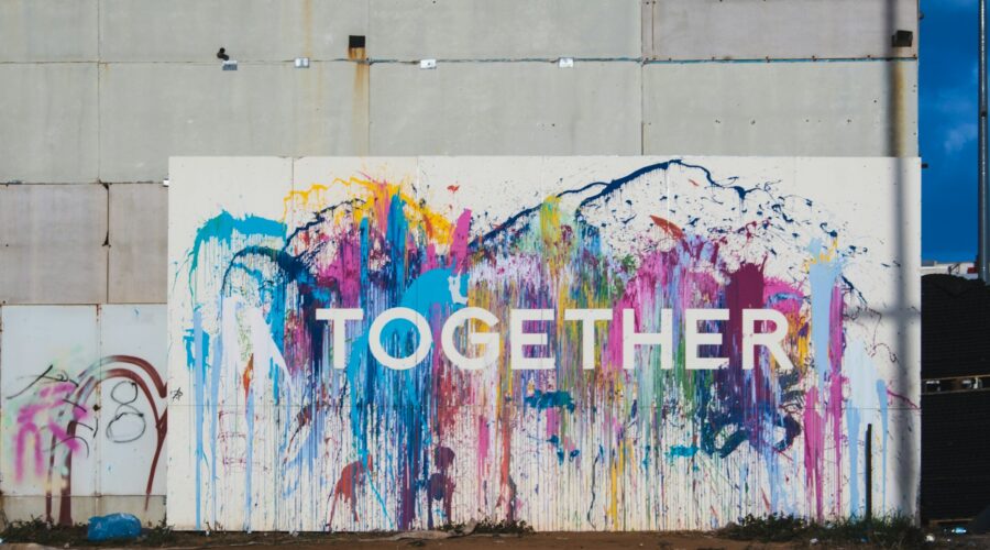 a wall painted in many colors, reads: "together"