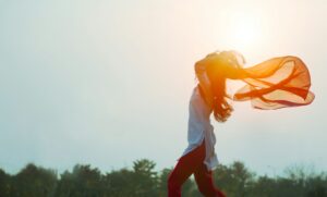 a woman, wind blowing her hair and scarf