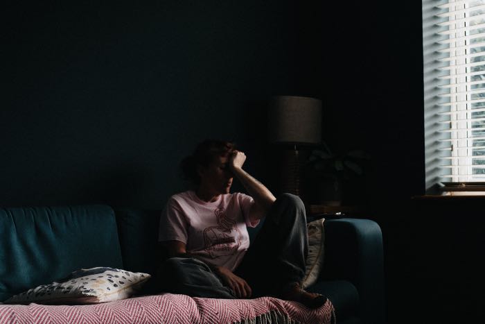 a photo of a woman on a couch, hand to her face.