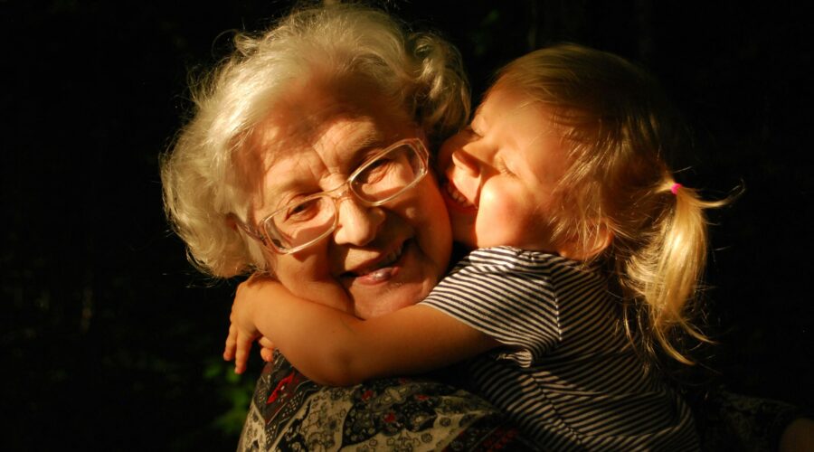 A photo of an older woman being hugged by a young girl
