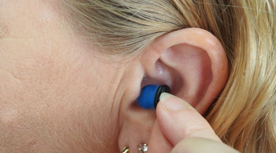 a photo of a person putting an "invisible" hearing aid in their ear