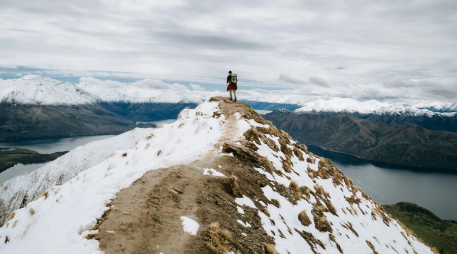 a photo of a person at the top of a snow-capped mountain