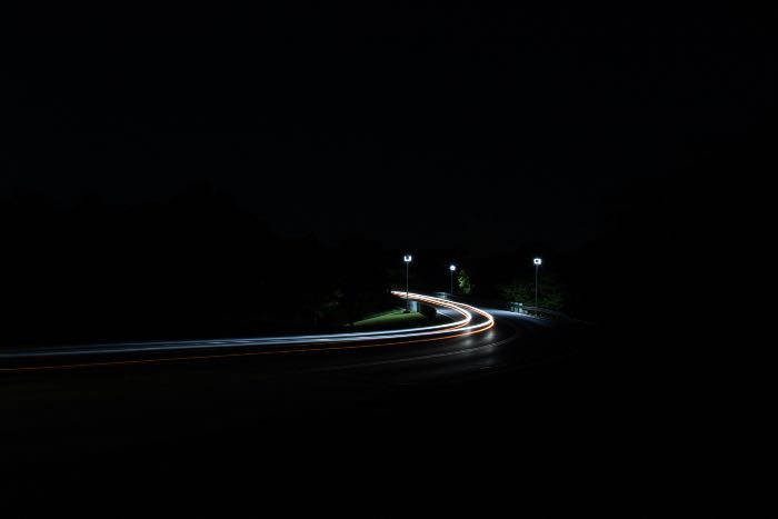 a photo of a road in darkness, lights revealing the curve